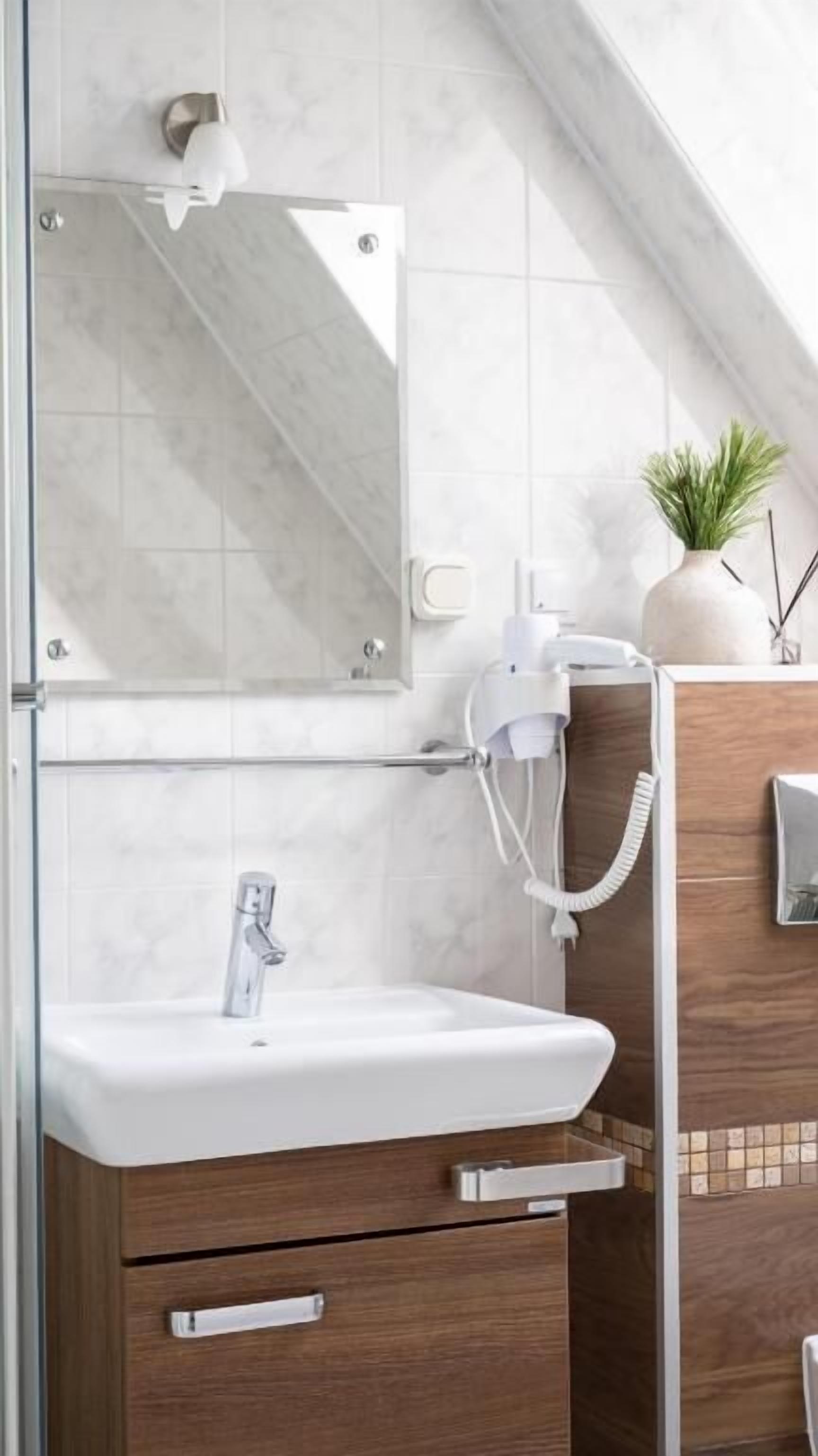 A bathroom with a white sink, a mirror, a towel rack, and a wooden cabinet.