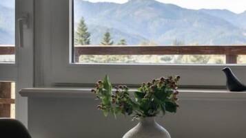 Una habitación con un ventanal grande, una mesa redonda y un florero con flores.