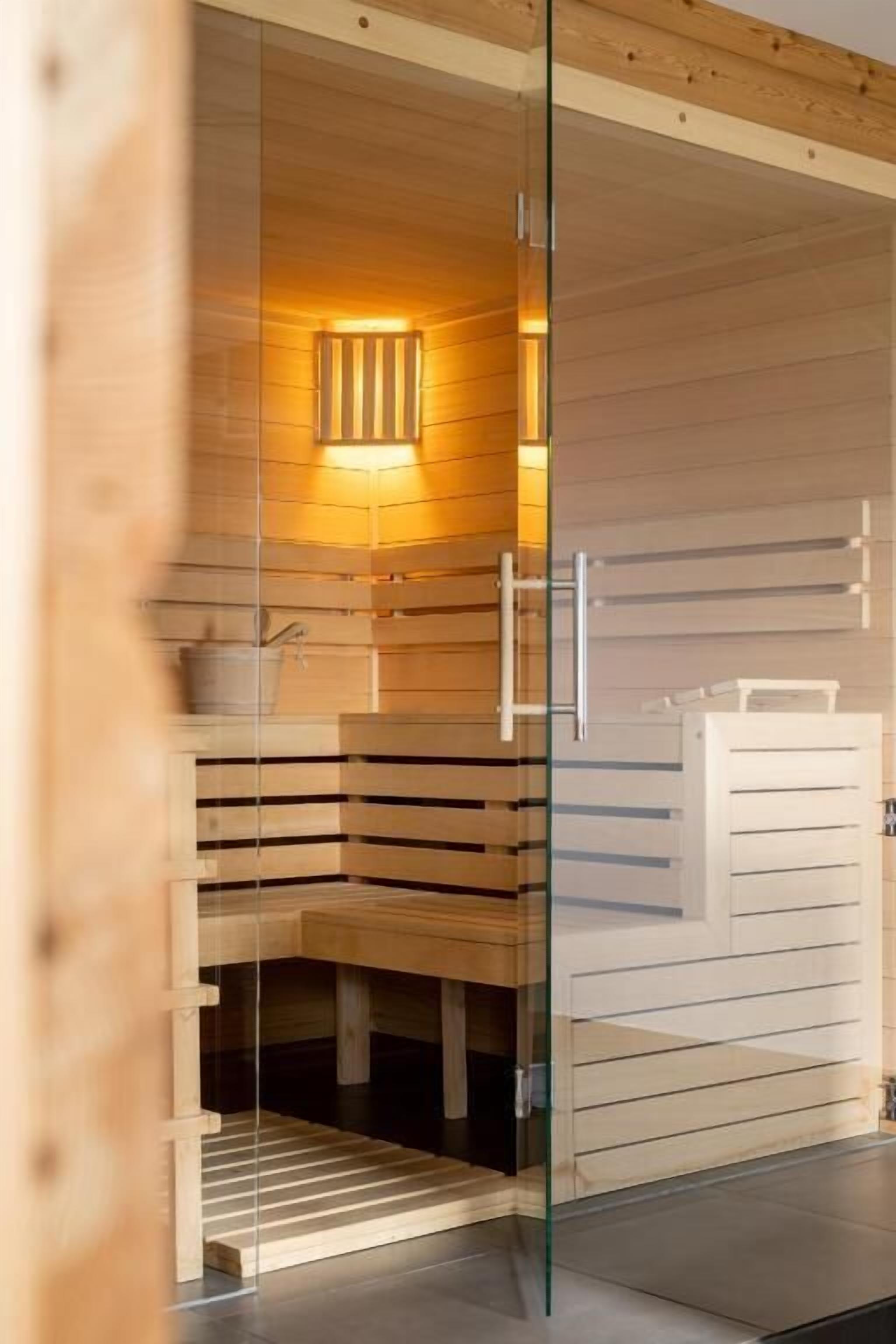 Una sauna con paredes de madera, una puerta de cristal y un banco.