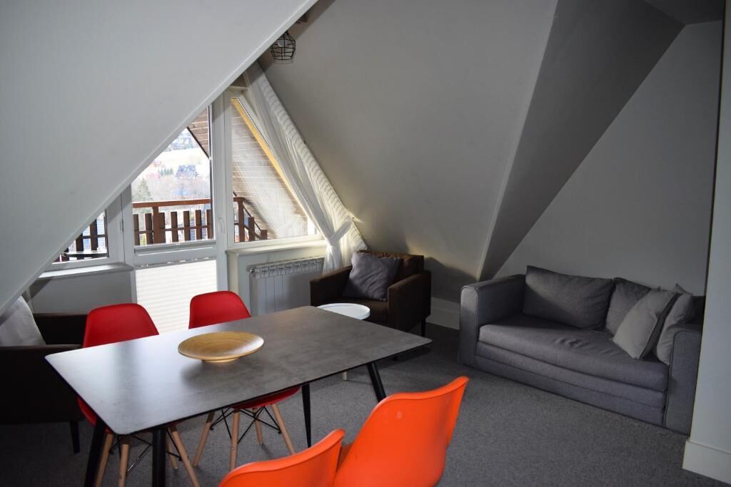 Een eethoek met een tafel en stoelen, een grijze bank en een raam met uitzicht.