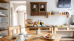 Una cucina con mobili in legno, un tavolo da pranzo con una tazza e pane, e diversi oggetti da cucina sul bancone.