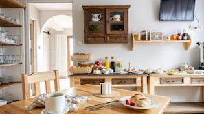 Una cocina con armarios de madera, una mesa de comedor con una taza y un plato, y varios utensilios de cocina sobre la encimera.