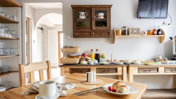 A kitchen with wooden cabinets, a dining table with a cup and bread, and various kitchen items on the counter. - Panorama Premium (Kościelisko)