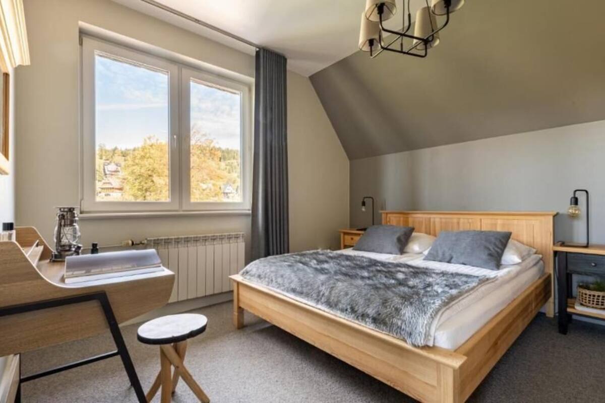 Un dormitorio con cama, escritorio, silla y ventana.