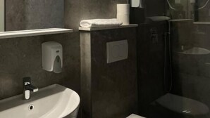 A modern bathroom with a sink, toilet, and glass shower enclosure. - Vue Mer Hotel (Ulcinj)