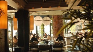 An indoor dining area with tables and chairs, large windows, and hanging lamps. - Vue Mer Hotel (Ulcinj)