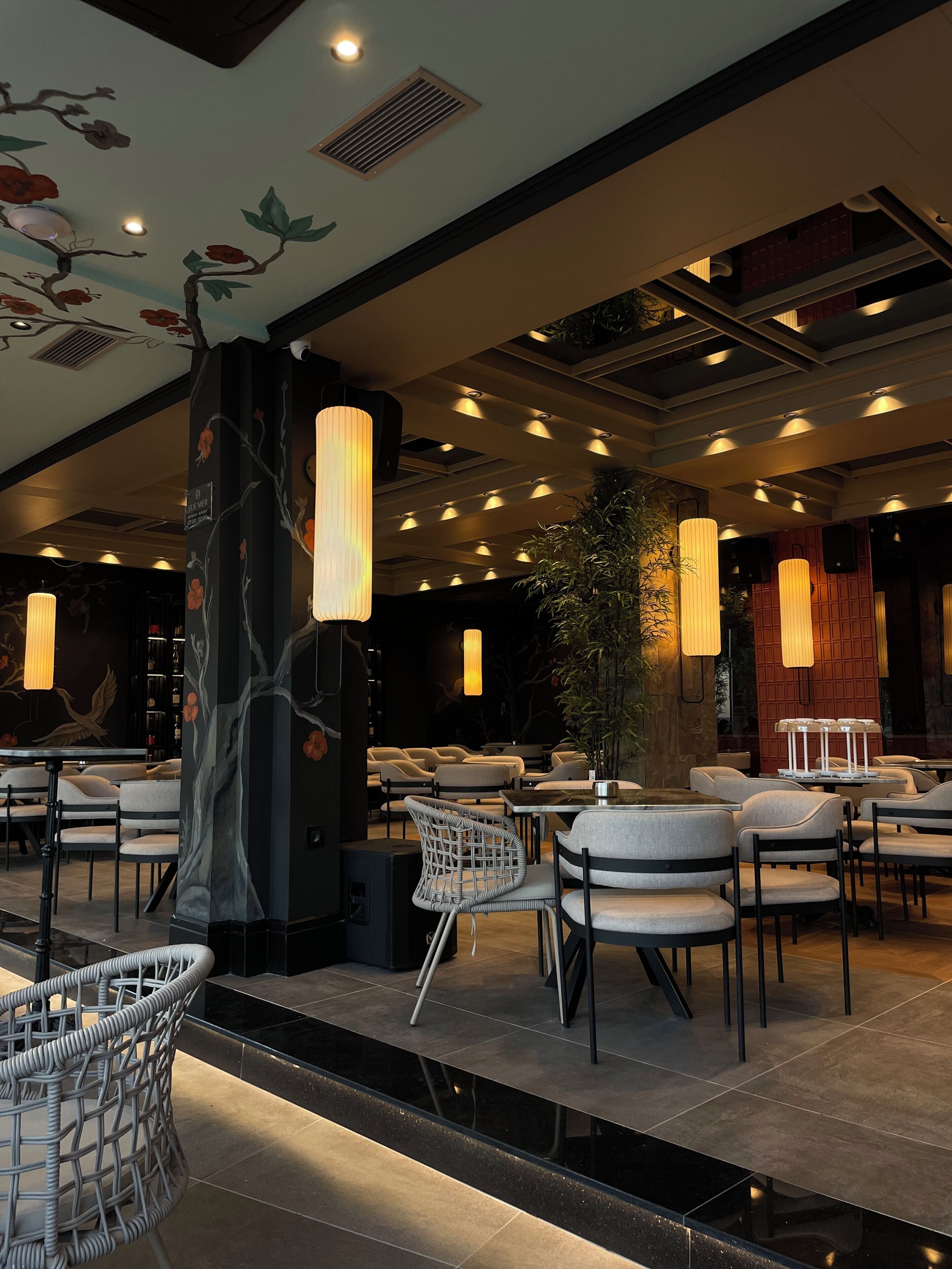 L’intérieur d’un restaurant, avec un mobilier moderne, des luminaires suspendus et des œuvres d’art décoratives sur les murs.
