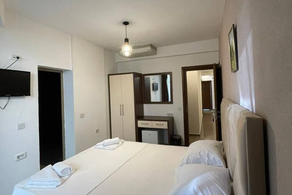 Un dormitorio con cama, escritorio, espejo y televisor.