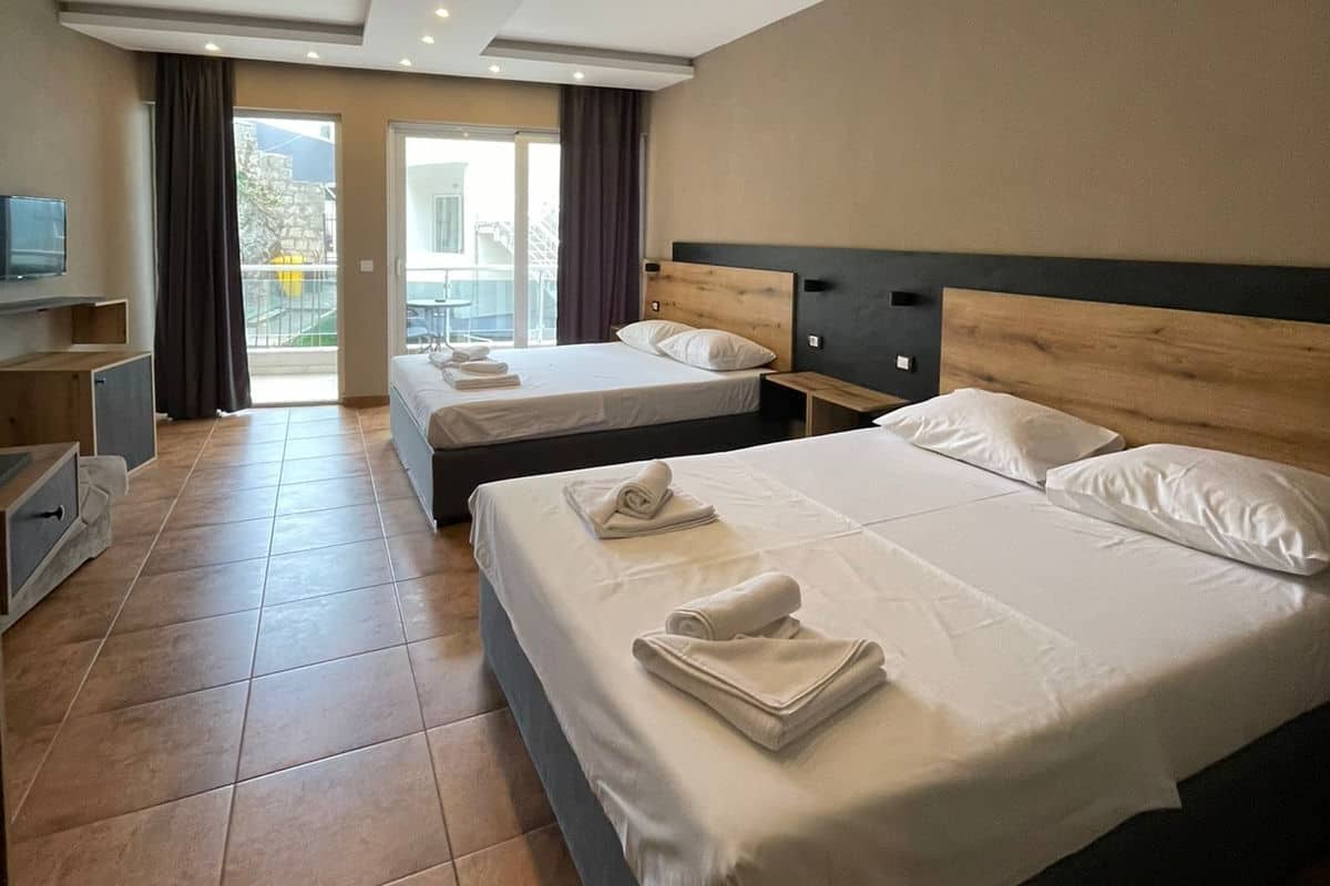 Habitación de hotel con dos camas, televisión, escritorio y un ventanal grande.