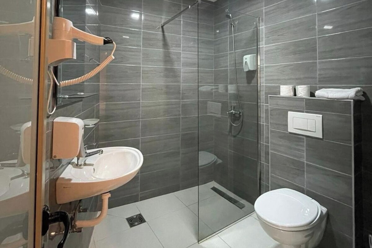A modern bathroom with a glass-enclosed shower, a white sink, and a toilet.