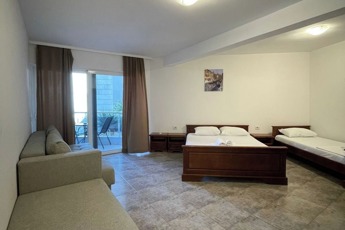 Habitación de hotel con cama, sofá, una mesita y vistas al exterior.