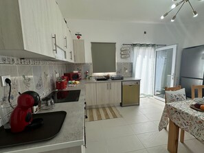 A kitchen with a microwave, toaster, and kettle, a dining area with a table and chairs, and a refrigerator. - Holiday Home 'Ar Doce' with Private Pool, Wi-Fi and Air Conditioning (Portel)