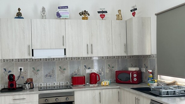 Une cuisine avec des meubles de couleur bois clair, une cuisinière, un four à micro-ondes et divers appareils de cuisine.