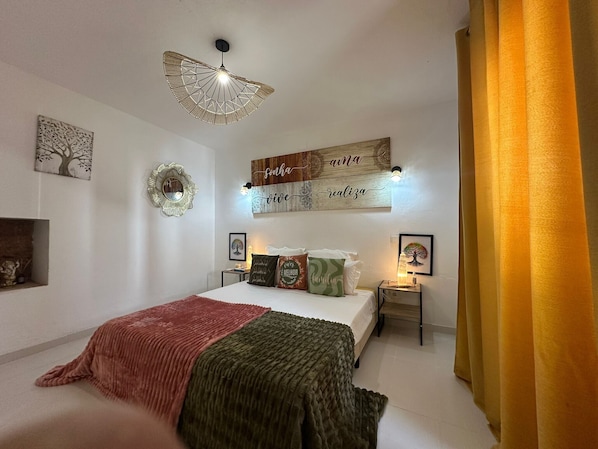 A bedroom with a bed, decorative wall art, a ceiling fan, and a bedside table.