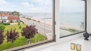 A coastal view from a window overlooking a road, beach, and residential area. - 4 Person Holiday Home in Hejls (Hejls)
