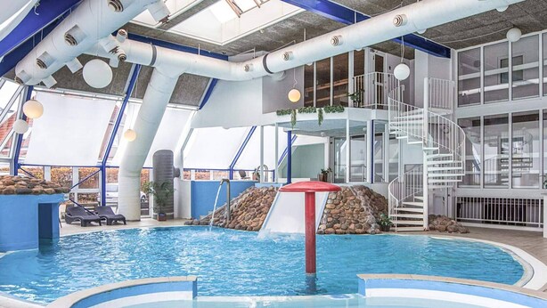 An indoor swimming pool with a slide, lounge chairs, and a staircase. - 4 Person Holiday Home in Hejls (Hejls)