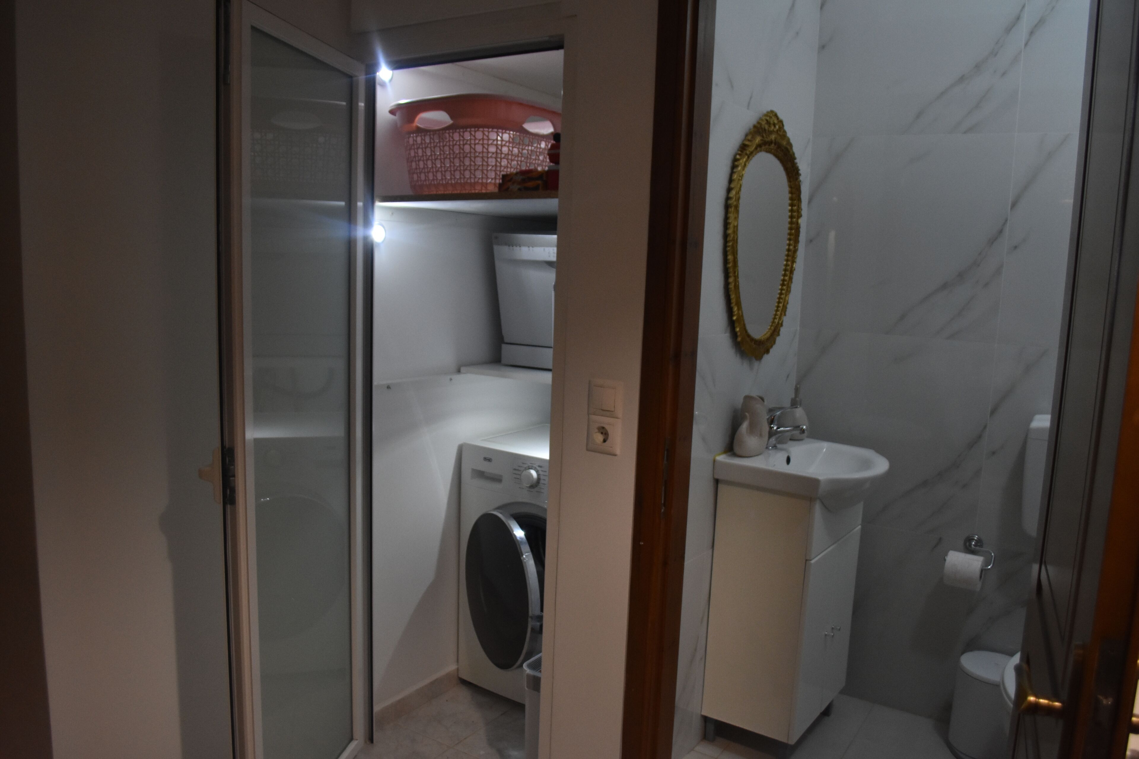 Une petite salle de bain équipée d’un lave-linge, d’un évier et de toilettes.