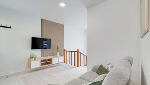 A modern living room with a flat-screen TV, wooden slat wall, built-in shelving, a staircase, and a sofa. - Gil House by Holiday Rental Madeira (São Vicente)