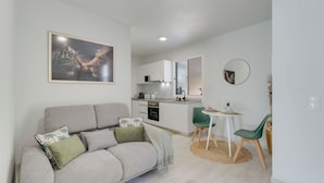 A modern living room with a sofa, a dining area with chairs, a kitchen in the background, and a framed picture on the wall. - Gil House by Holiday Rental Madeira (São Vicente)