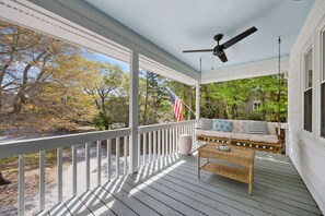 Eine überdachte Veranda mit einer Schaukel, einem Korbstuhl und einer amerikanischen Flagge.