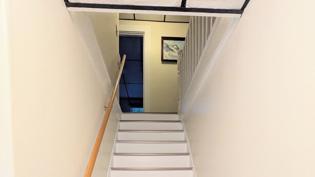 Una scala con corrimano in legno e una porta blu in cima.