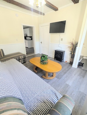 Una sala de estar con un sofá, una mesa de centro de madera, un televisor montado en la pared y una chimenea.