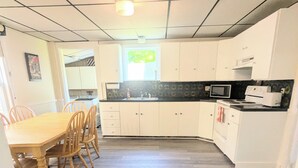 Una cucina con mobili bianchi, un tavolo da pranzo con sedie, un forno a microonde e un piano cottura.