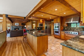 A spacious kitchen with wooden cabinetry, a central island, and a stone backsplash. - Alpenview Lodge | Best Of Breck (Breckenridge)