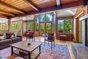 A spacious living room with a wooden ceiling, large windows, a sofa, chairs, and a coffee table. - Alpenview Lodge. Views, Hot Tub, 5 mins. to Breck! (Breckenridge)