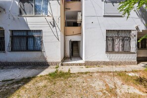 A narrow alleyway between two buildings with barred windows and a small door. - Perla Apartment 2BR Beachside (Golem)