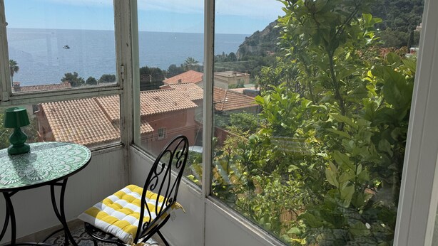 A conservatory with a view of the sea, a table with a chair, and a green lamp. - Petite Eze (Provence-Alpes-Côte d'Azur)