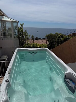 Ett bubbelbad med fri utsikt över havet och en inglasad uteplats.