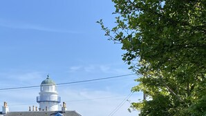 Un bâtiment blanc avec des ornements bleus, un dôme et une cour clôturée avec un banc.