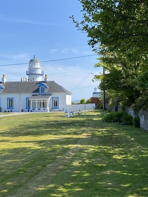 Un bĂątiment Ă la façade blanche et bleue, surmontĂ© dâun dĂŽme, et dotĂ© dâune courClose dĂ©limitĂ©e par une clĂŽture, oĂč se trouve un banc.