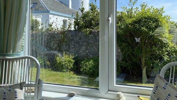 Une pièce avec vue sur un phare, une petite table, une chaise et une fenêtre avec des rideaux.