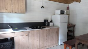 A compact kitchen with a gas stove, a coffee maker, a toaster, and a white refrigerator. - "La Maison Nomade" vacation rental in a paradise-like setting. Woods. Ponds. Very quiet (CHAGNY)
