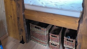 A rustic bedroom with a wooden bed frame, a window with a view, and built-in shelves with decorative items. - "La Maison Nomade" vacation rental in a paradise-like setting. Woods. Ponds. Very quiet (CHAGNY)