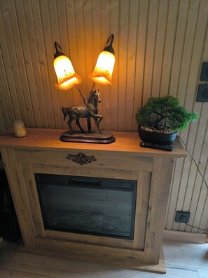 Un meuble en bois surmonté d’une statuette de cheval décorative, d’une plante en pot et d’une télécommande.
