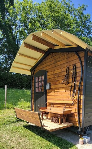 Une cabane en bois avec une véranda, une porte dotée de fenêtres et un banc.