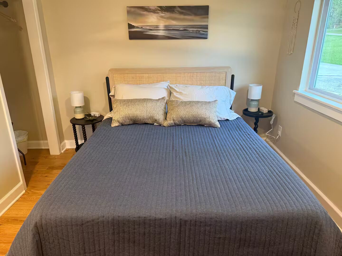 Un dormitorio con una cama, dos lámparas de noche, una obra de arte en la pared y una ventana.
