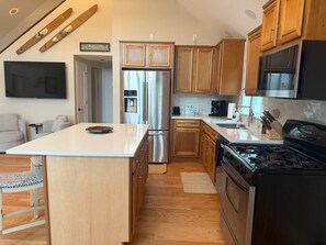 A modern kitchen with wooden cabinets, stainless steel appliances, and a central island.