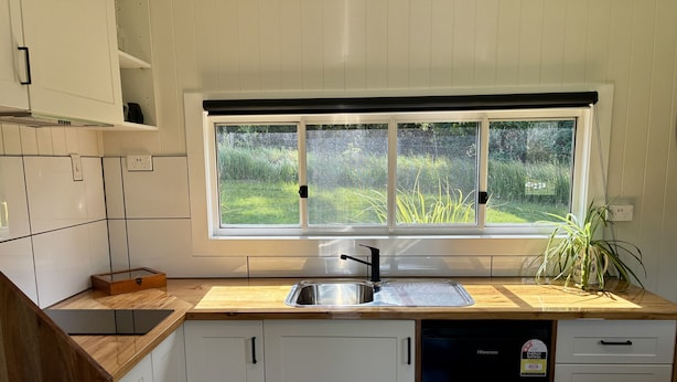 A kitchen with a window, a sink, cabinets, and a dishwasher.