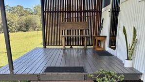 A wooden deck with a bench and a potted plant.