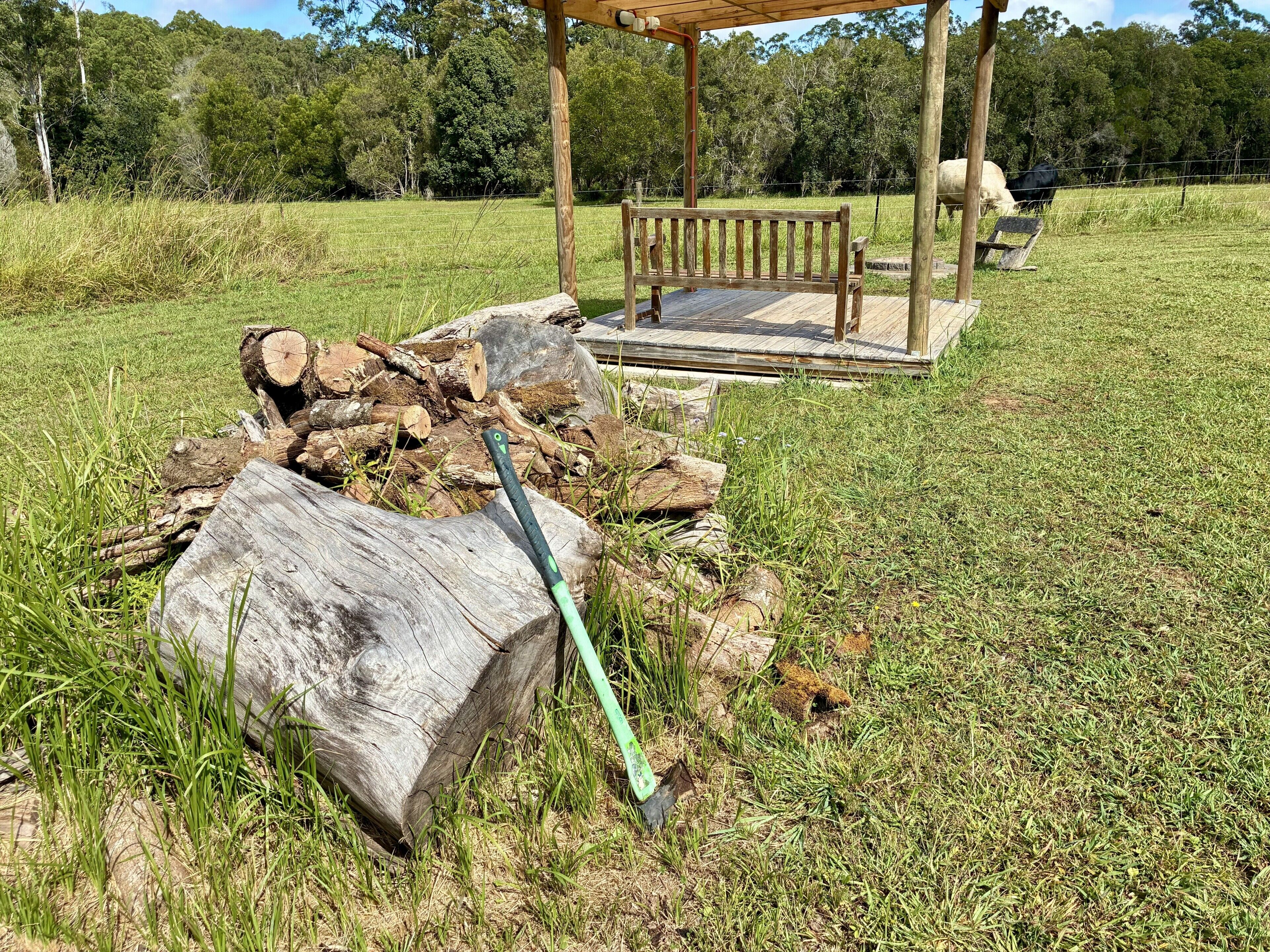 Un mirador de madera con un banco, rodeado de un campo cubierto de césped y árboles.