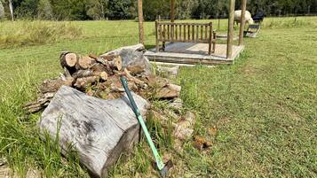 Un mirador de madera con un banco, rodeado de un campo cubierto de césped y árboles.