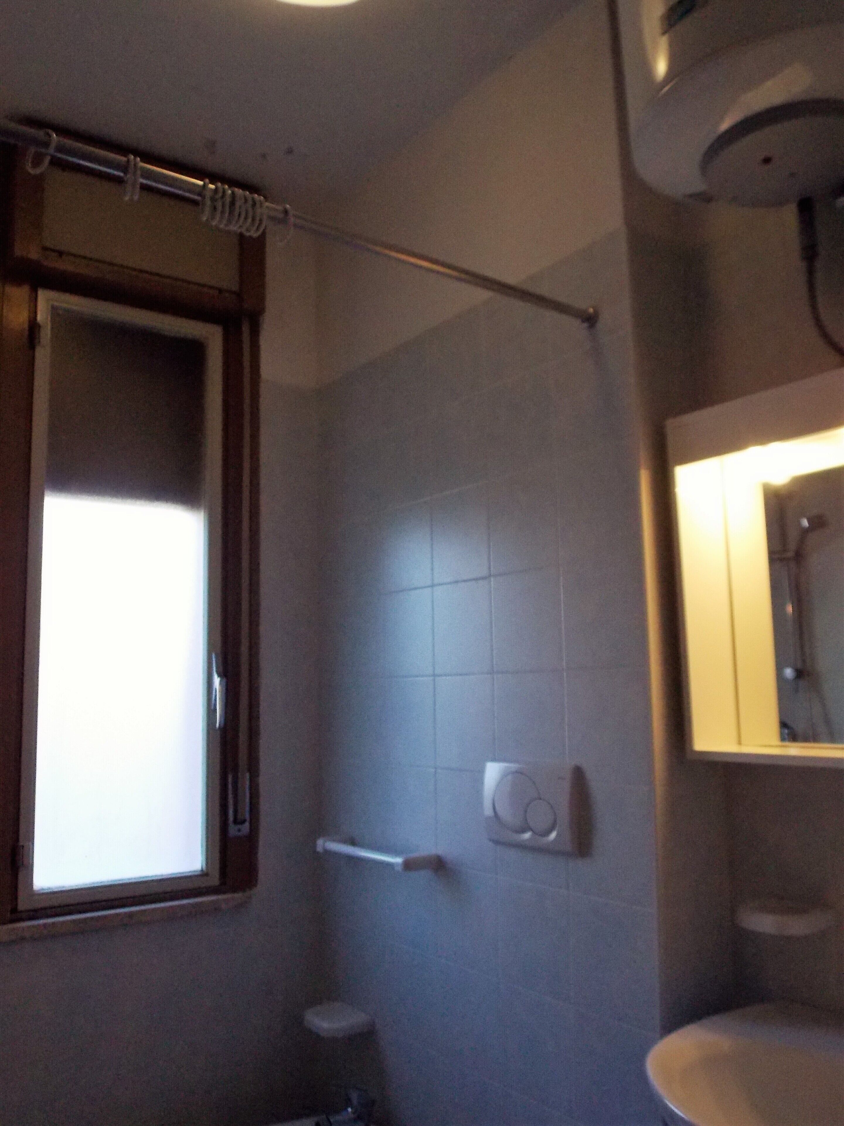 Une salle de bain avec une fenêtre, une douche, des toilettes et un lavabo.