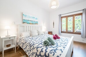 Ein Schlafzimmer mit einem Bett, einem Gemälde, einem Fenster und einem Nachttisch.