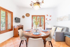 Ein Essbereich mit einem runden Tisch für vier Personen, einer Couch und einem Fernseher an der Wand.
