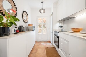 Eine moderne Küche mit weißen Schränken, einer großen Holtschüssel, einer Mikrowelle und einem Blumentopf.