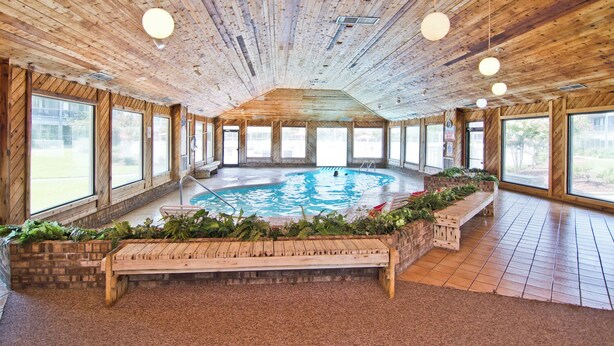 Interior em madeira com piscina central, janelas amplas e um banco.
